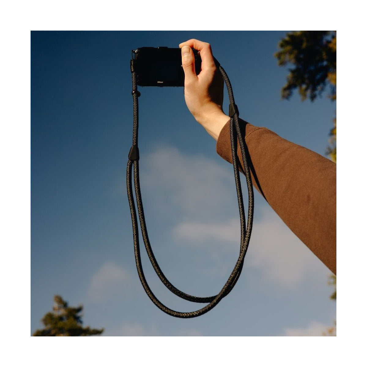 Peak Design Mobile Crossbody Strap (Black) — black strap held with compact camera view